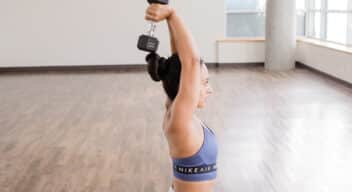 Woman doing a tricep exercise with a hand weight.